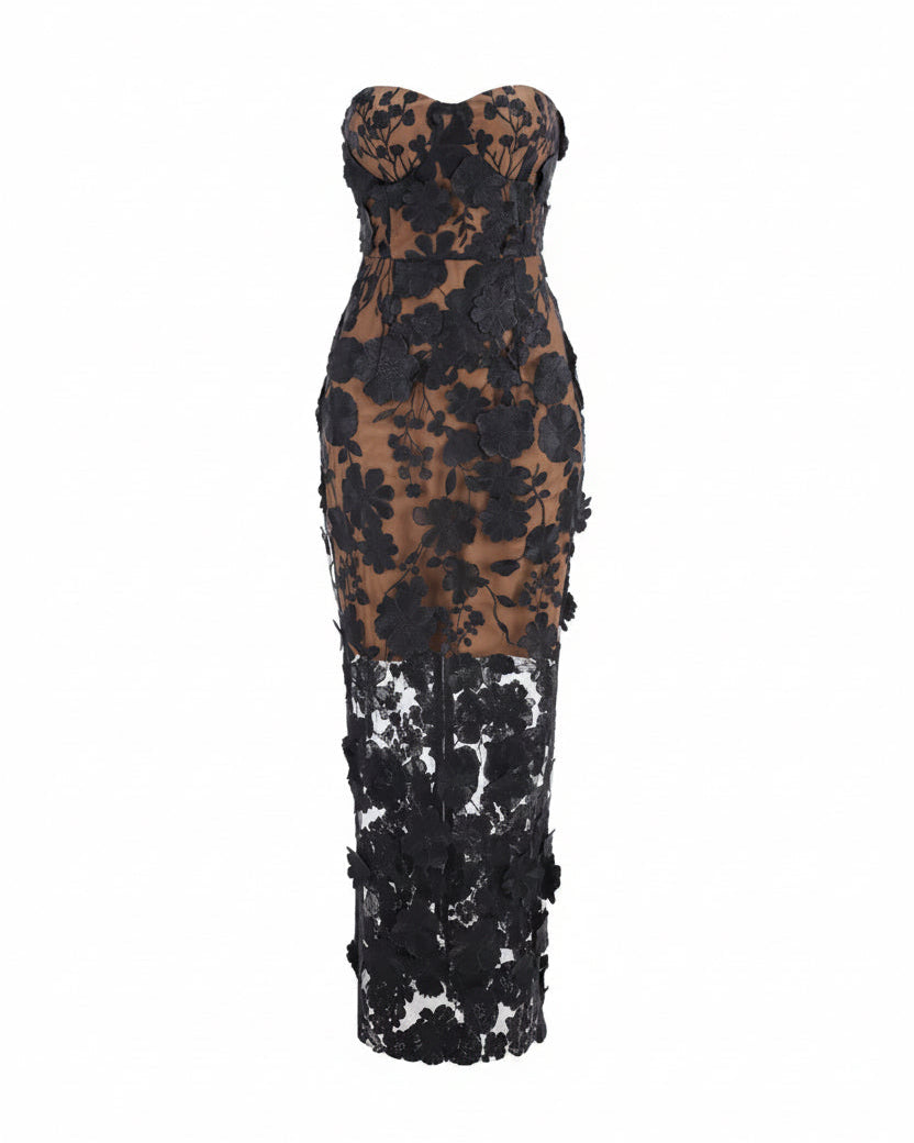 A strapless bodycon maxi dress featuring a sheer brown mesh upper section with black floral applique, transitioning into a solid black lace lower skirt, shown against a plain white background.